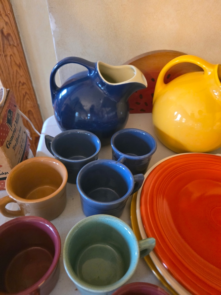 Colorful ceramic pitchers, mugs, and dishes at an estate sale