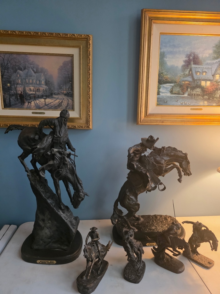 Framed artwork and decorative horse sculptures at an estate sale