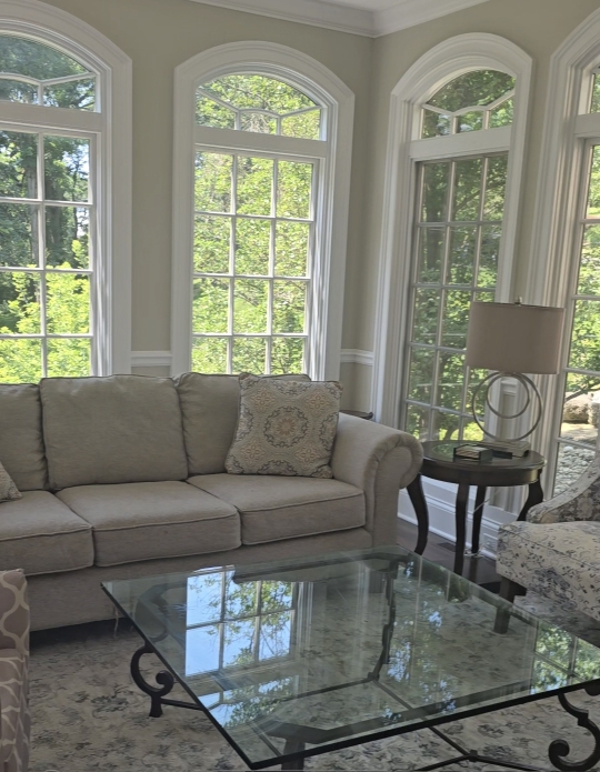 Living room furniture arranged in a bright sunroom